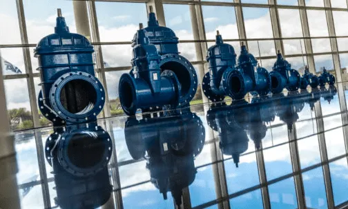 Large blue AVK industrial parts on a blank floor with a window facade behind
