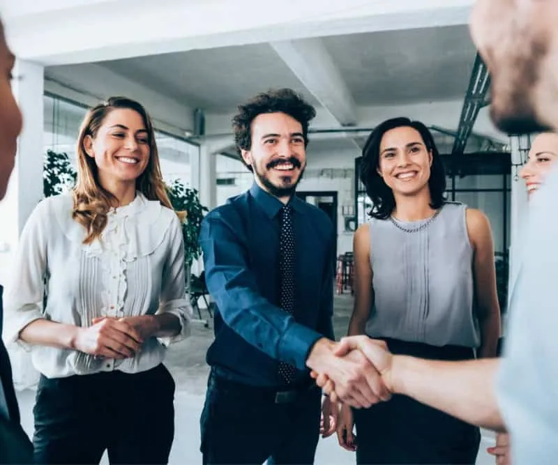 6 Two people shaking hands with their colleagues around them