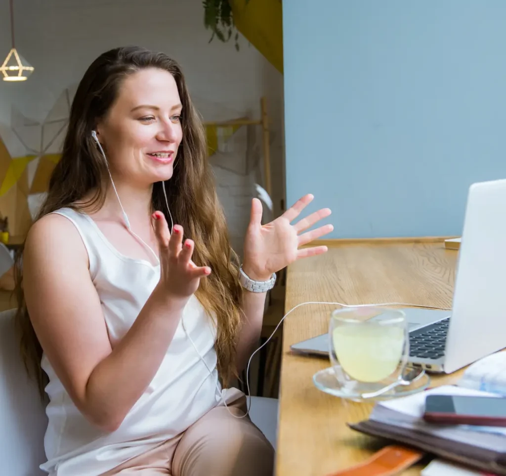 Woman attending online meeting on her laptop smiling and talking with gesturing hands